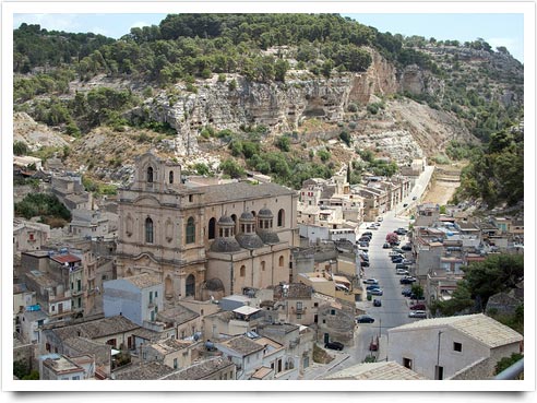 La città di Scicli sorge all'incrocio di tre valloni, con case da ogni parte su per i dirupi, una grande piazza in basso a cavallo di una fiumara, e antichi fabbricati ecclesiastici che coronano in più punti, come acropoli barocche, il semicerchio delle altitudini.